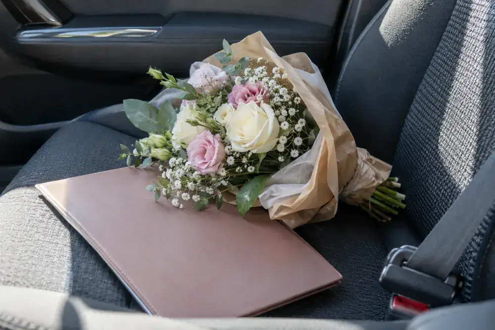 Imagen generada: Ramo pequeño y carpeta cerrada en el asiento de un automóvil.