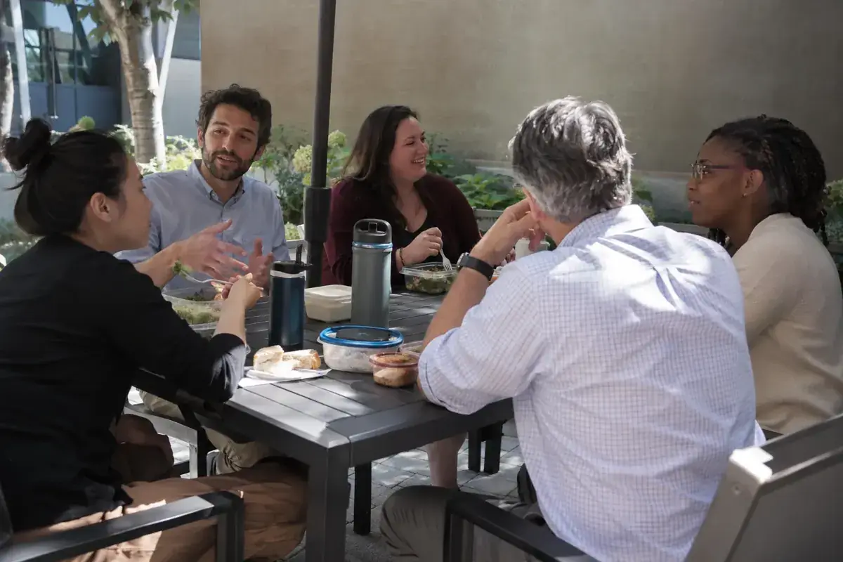 Colegas conversan durante una comida informal en un patio.