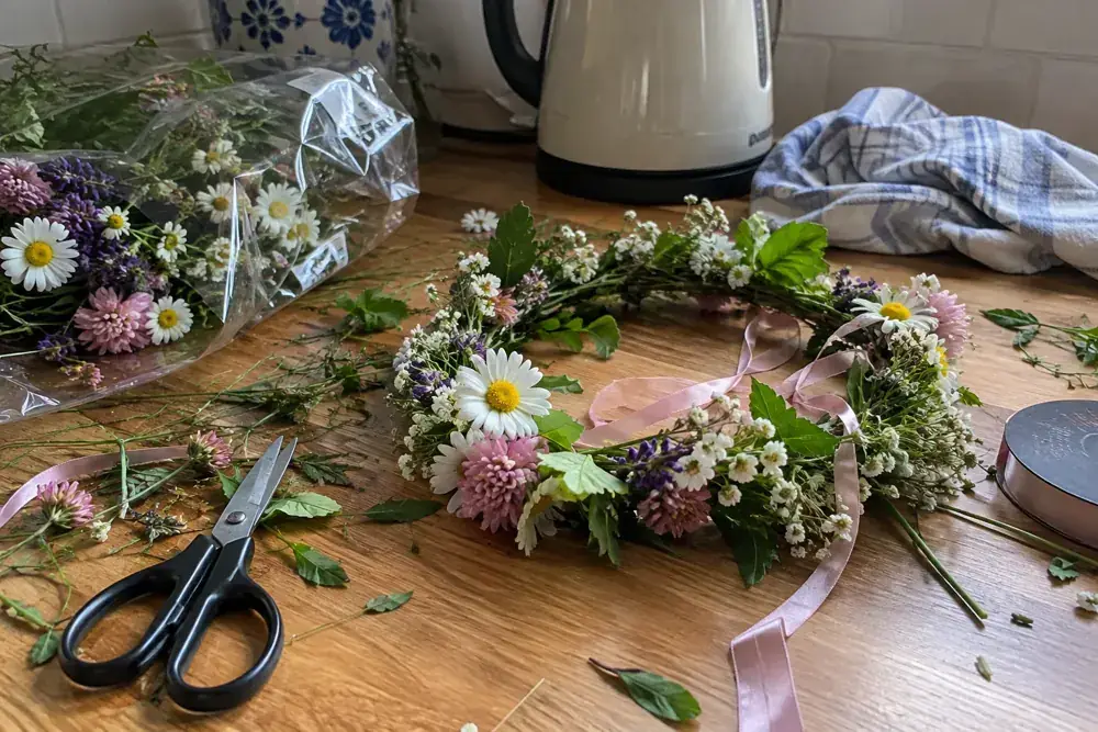 Imagen generada: Flores, cintas y tijeras sobre una mesa después de preparar coronas florales.