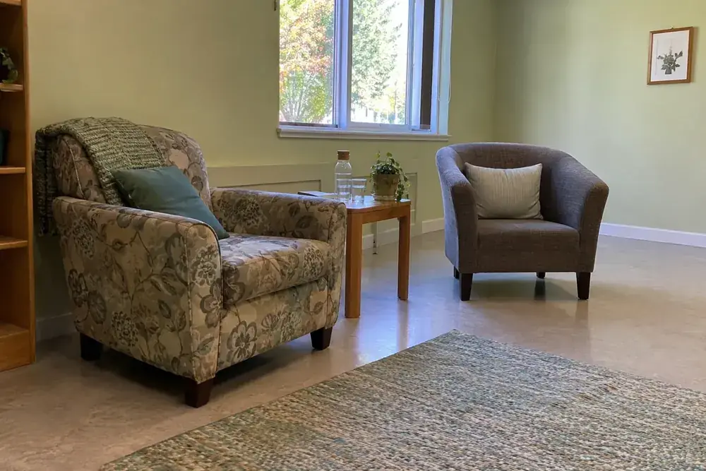 Dos asientos y agua en un rincón tranquilo de una sala comunitaria.
