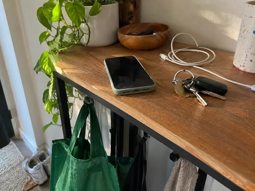 Imagen generada: Teléfono, llaves y cable sobre un mueble junto a la entrada de casa.