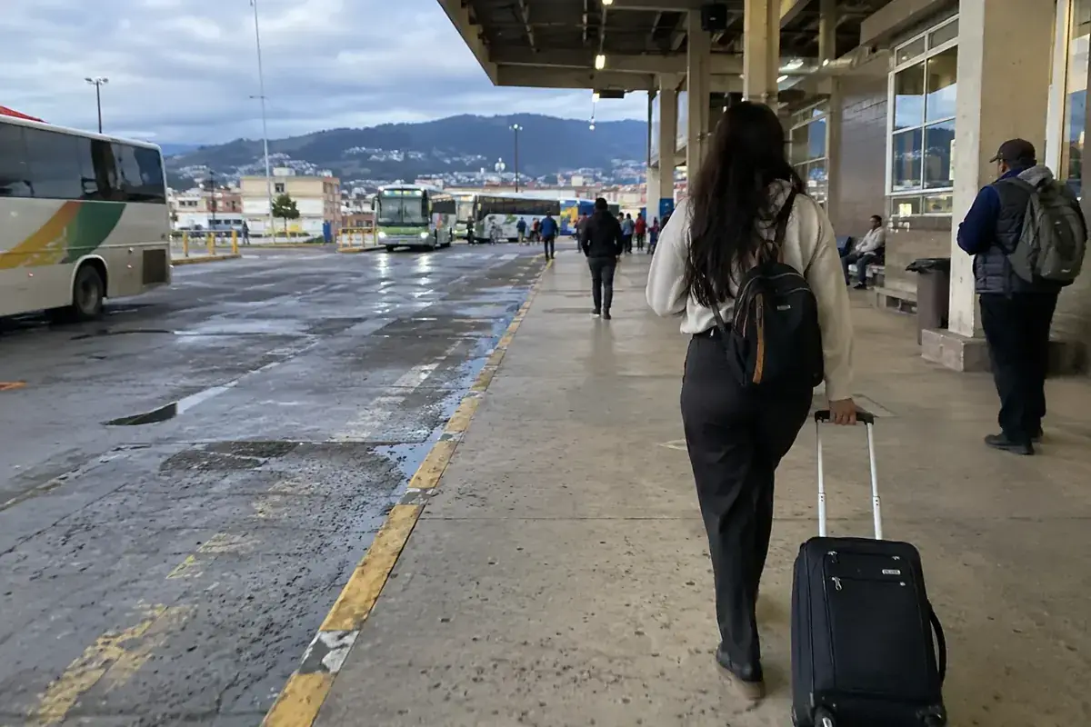 Persona con maleta de ruedas al llegar a una terminal de autobuses.