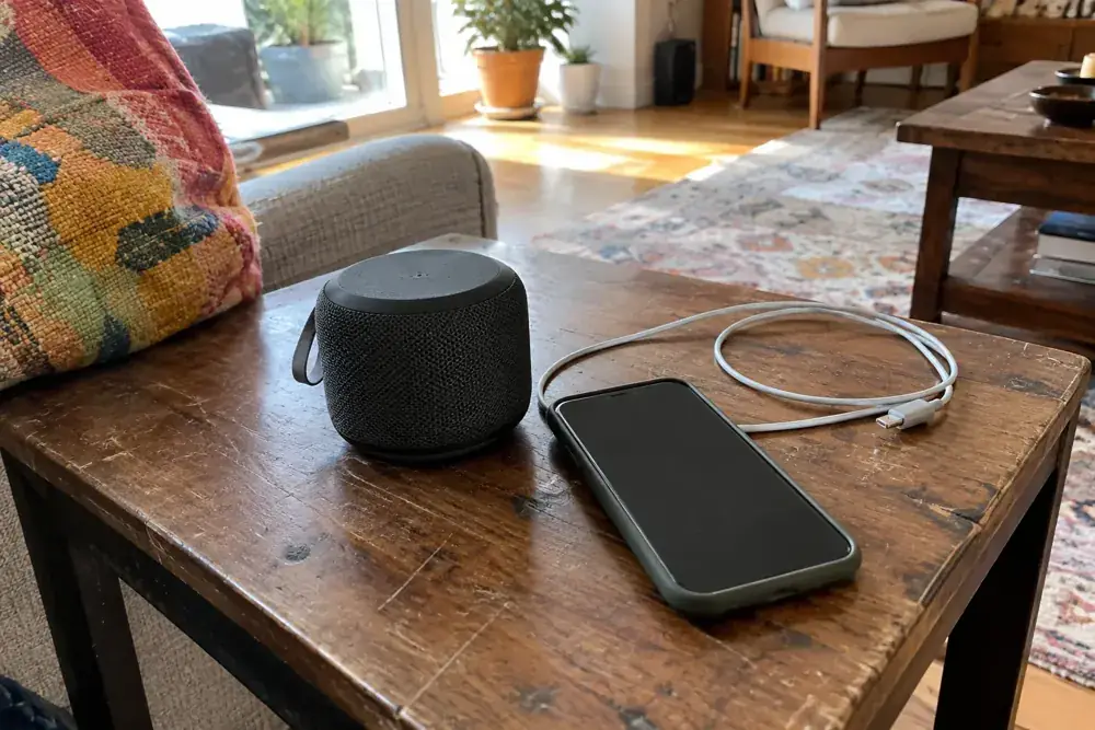 Bocina, teléfono y cable sobre una mesa auxiliar usada.