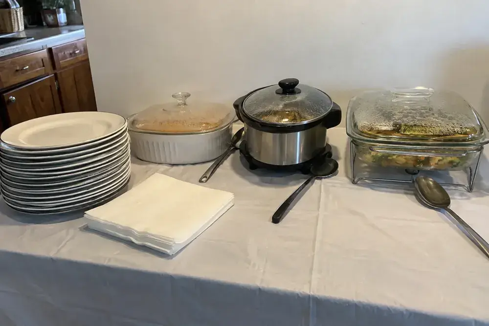 Platos, recipientes cubiertos, cucharas y servilletas en una estación sencilla de servicio.