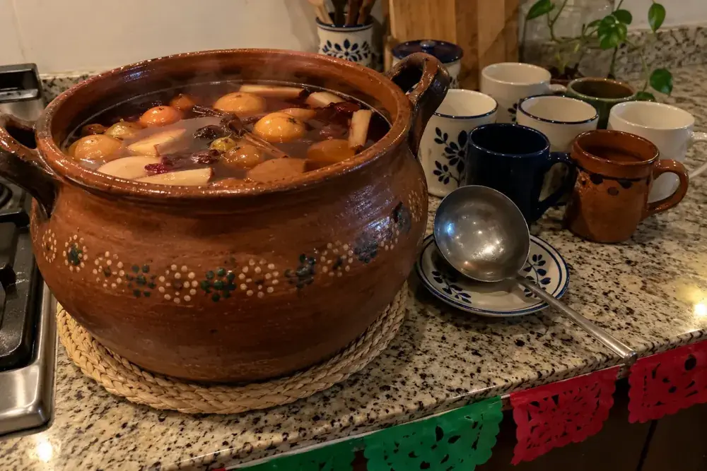 Olla de ponche, cucharón y tazas preparados para una posada.